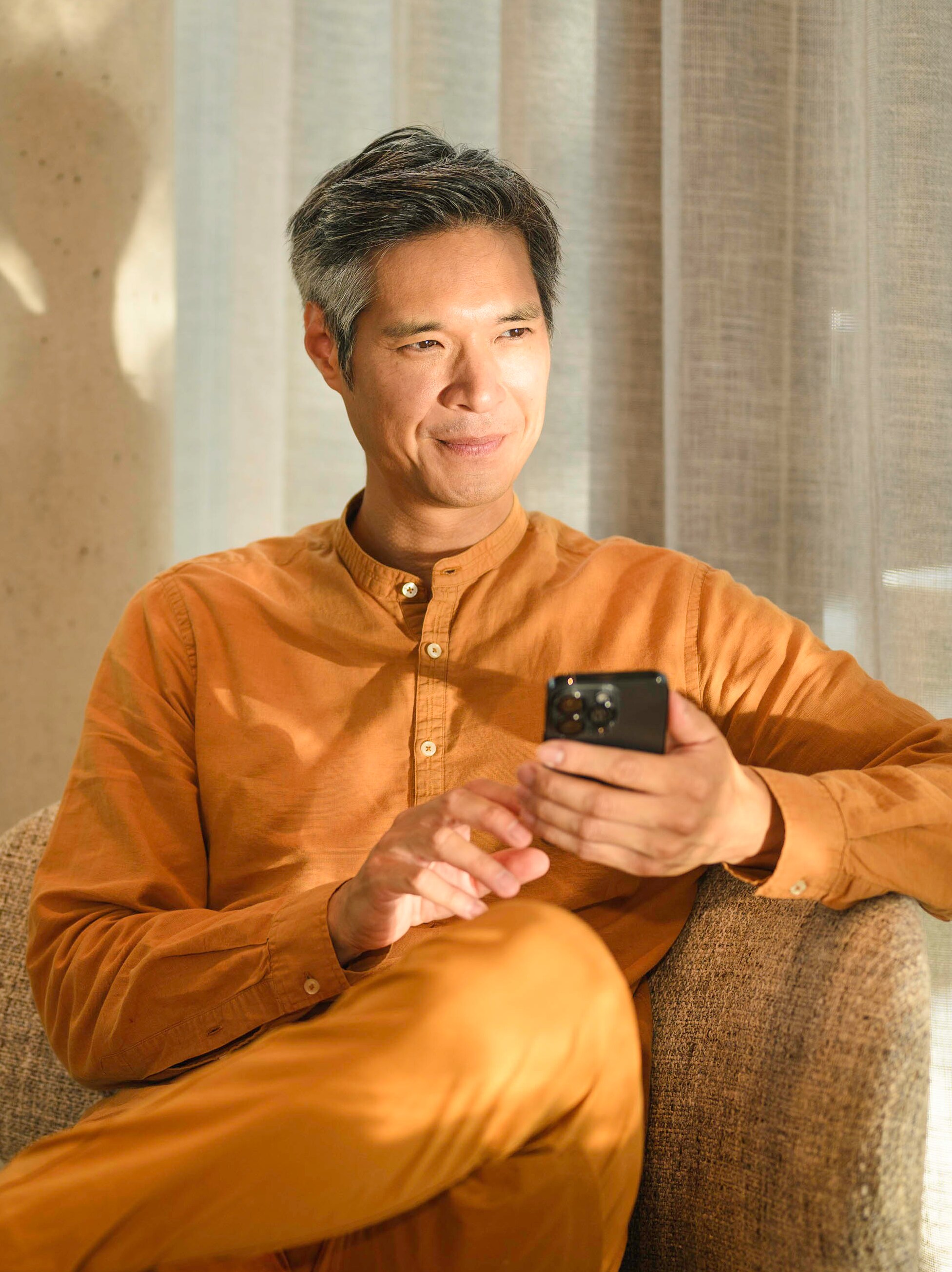 一人座於梳化上流動設備，手持及向遠處眺望