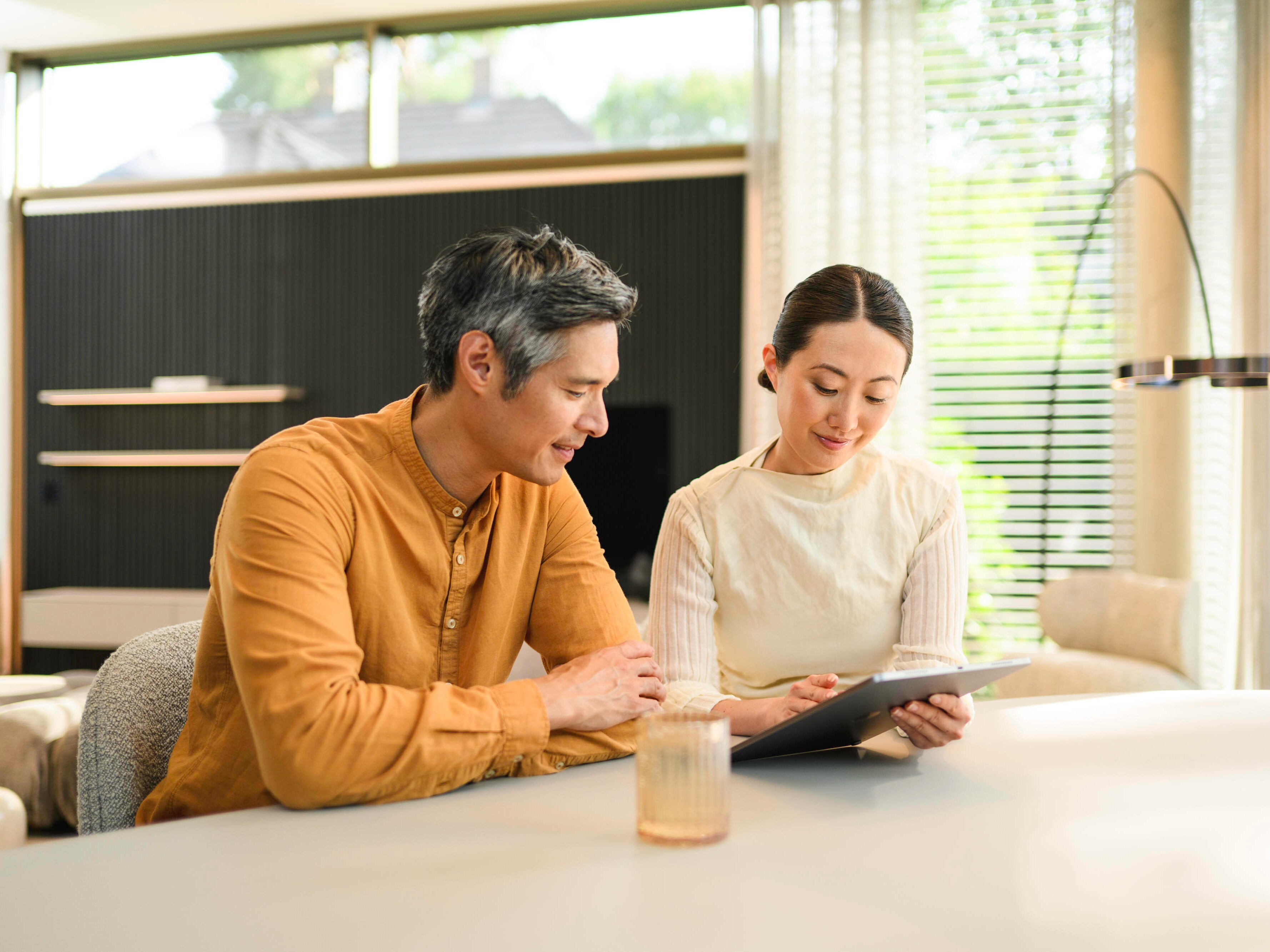 Two people sitting at a bench and looking at a mobile device.