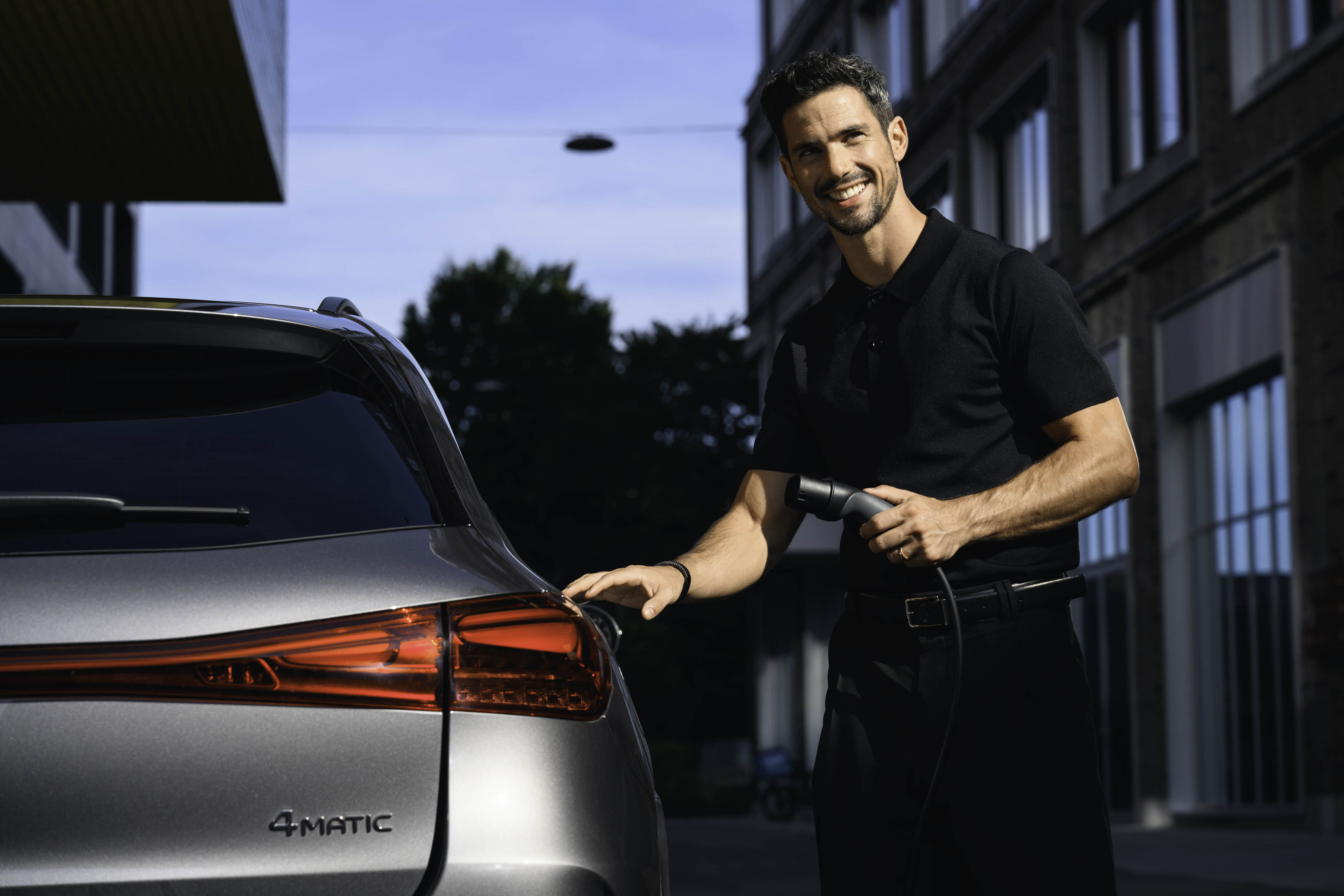 A person holding a charging cable and preparing to charge a Mercedes-Benz vehicle. Latest offer for EQ models from Mercedes-Benz Financial Services