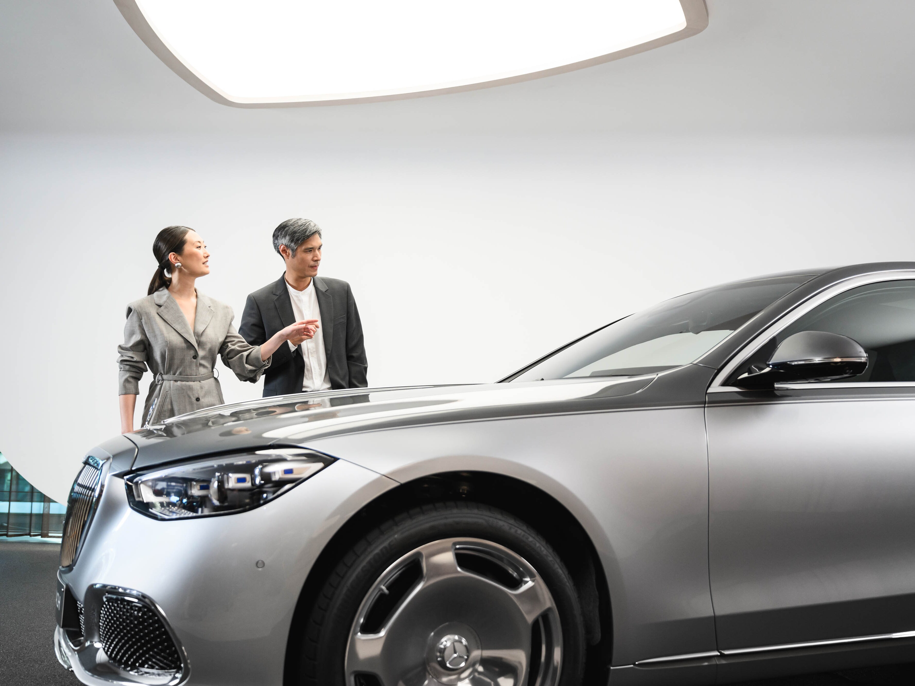Two people in a Mercedes-Benz showroom and viewing a car.