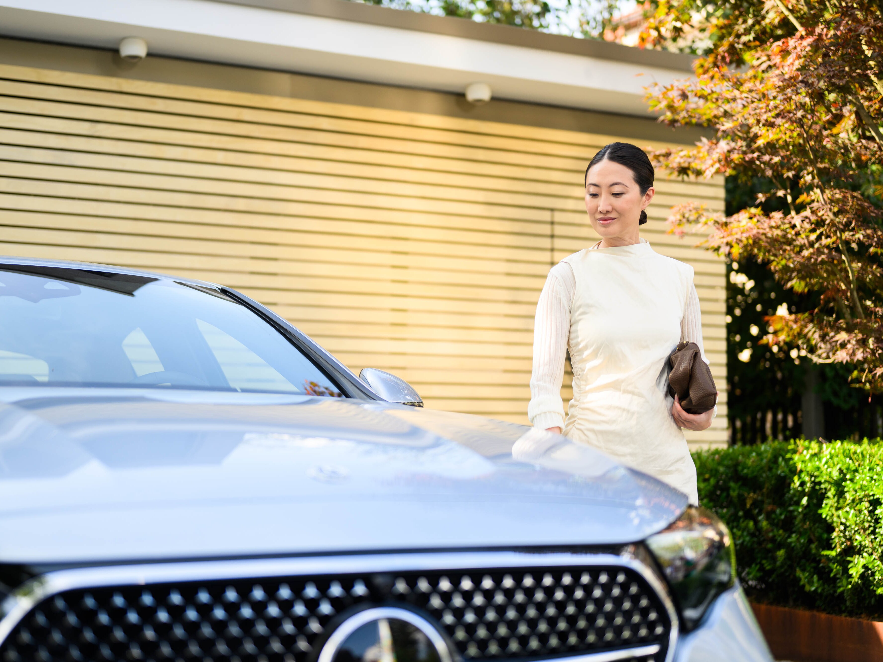 A person walking next to a Mercedes-Benz vehicle and looking at the car