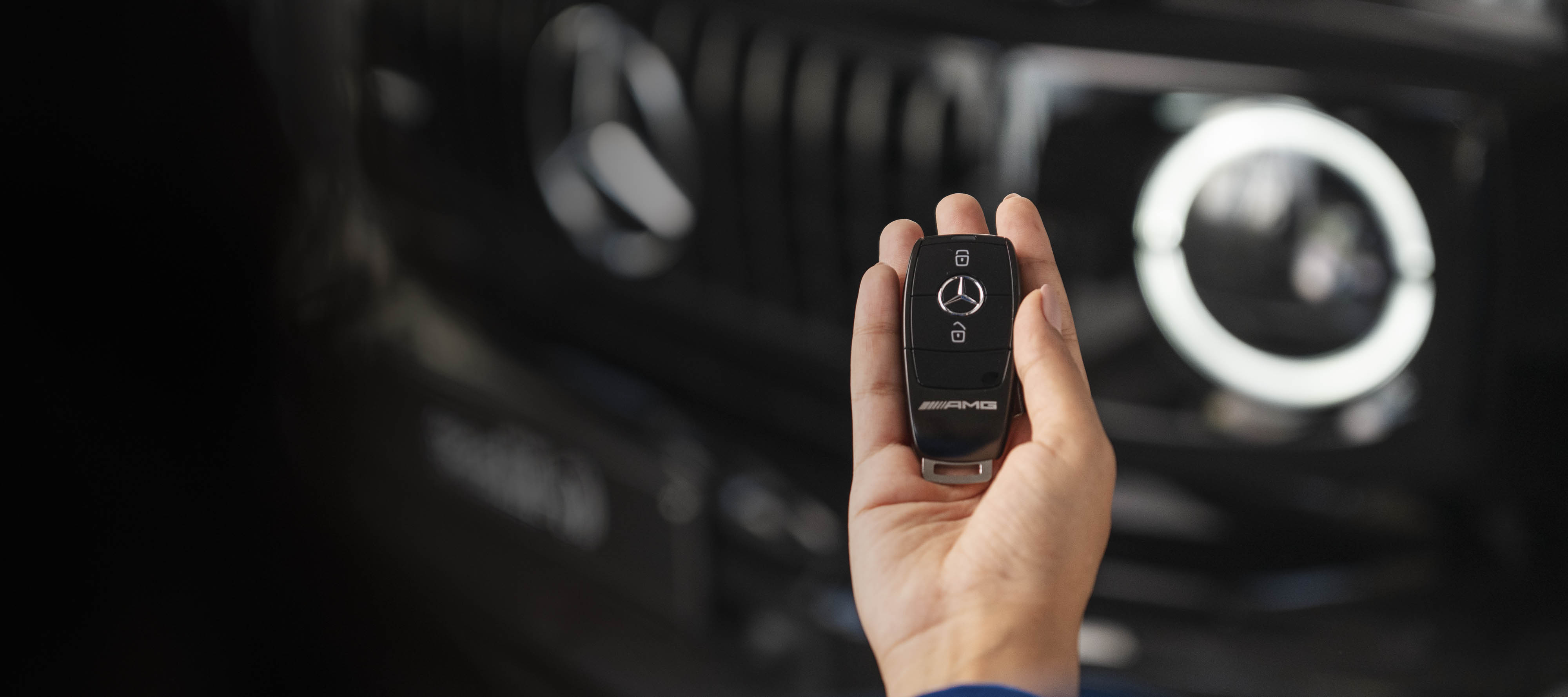 Financing offers for your Mercedes-Benz A person holding a Mercedes-Benz car key and in front of a Mercedes-Benz vehicle.