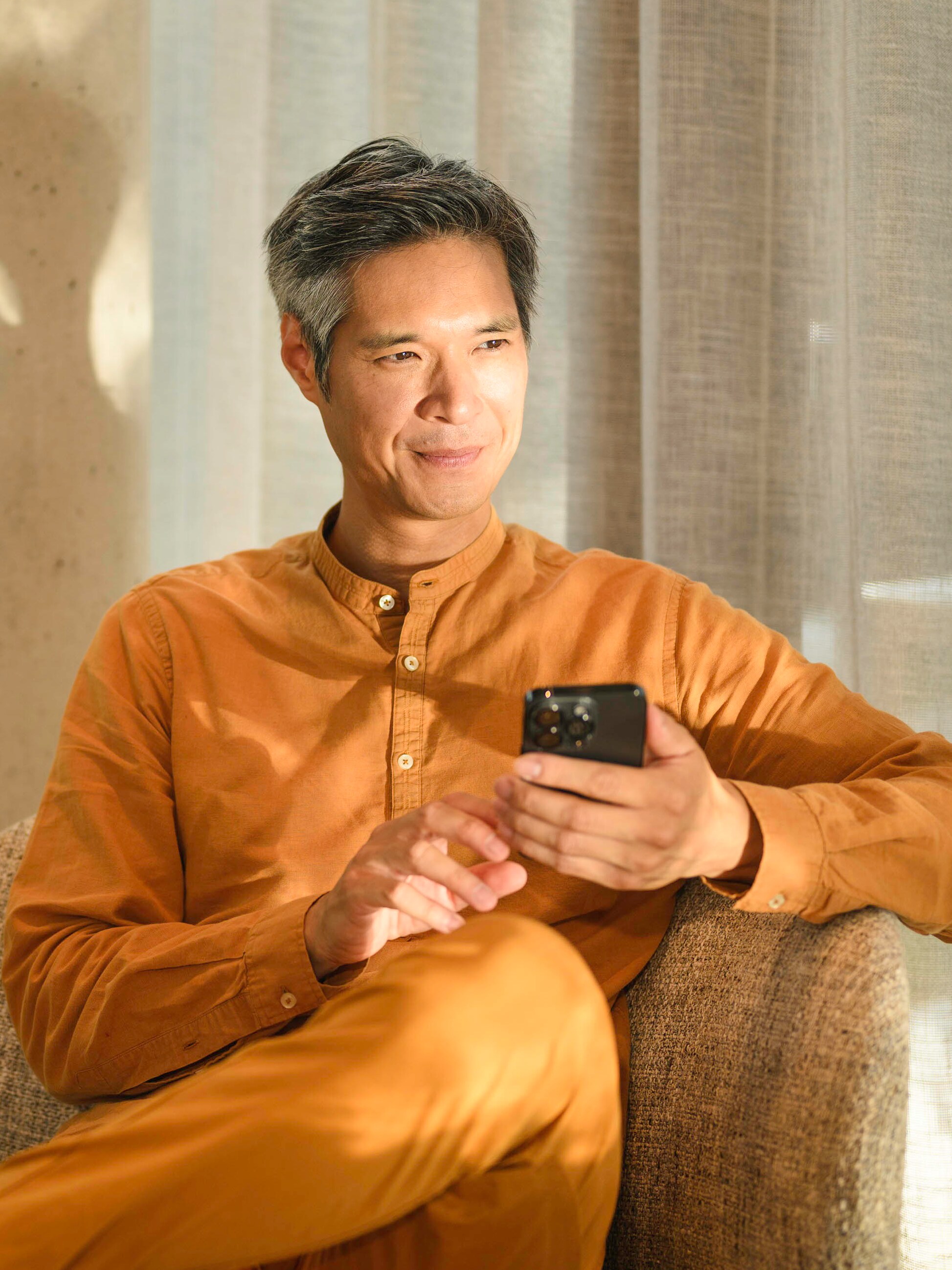 一人座於梳化上流動設備，手持及向遠處眺望​