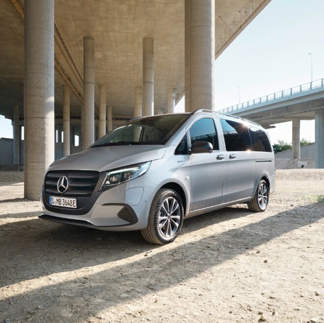 The Mercedes-Benz Vito Tourer is parked in front of a glass building.
