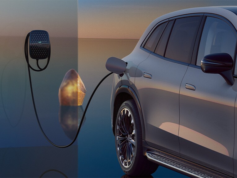 EQS SUV 在充電過程中的偏側視圖，連接到 Mercedes-Benz 掛牆式充電箱充電。