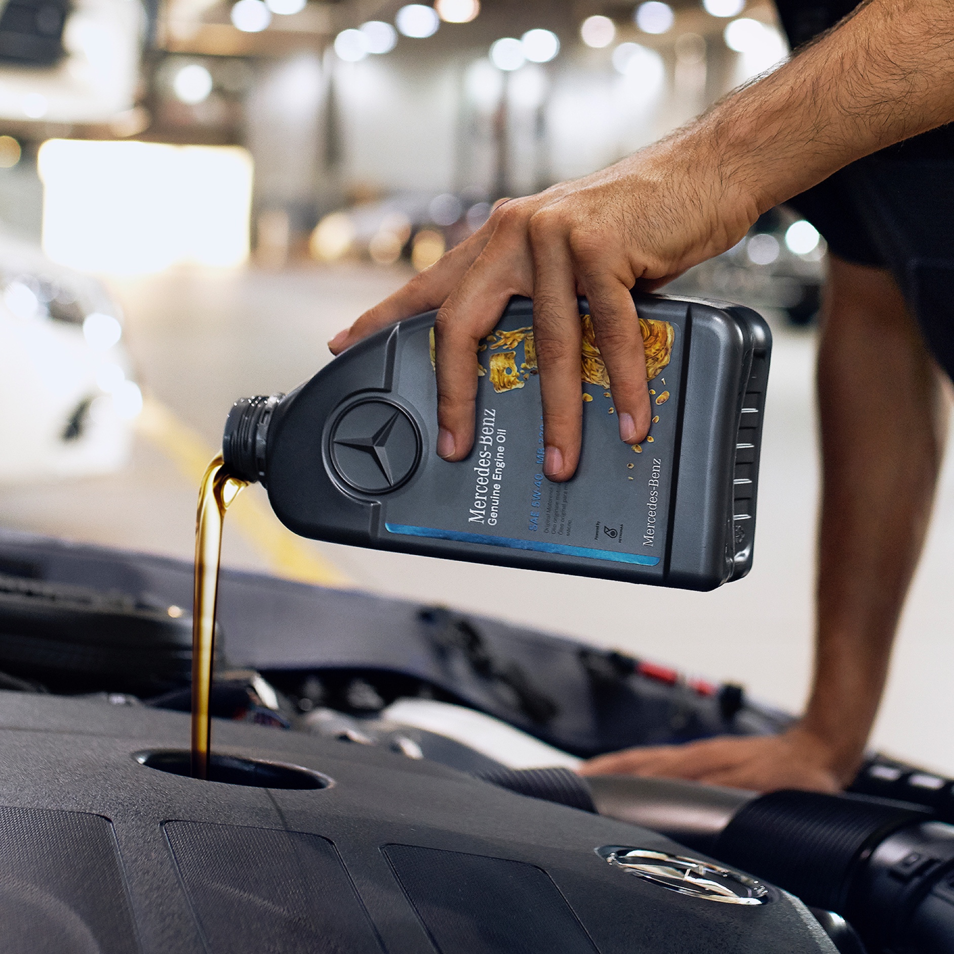 A person pouring engine oil into the Mercedes-Benz vehicle. Engine oil | Mercedes-Benz