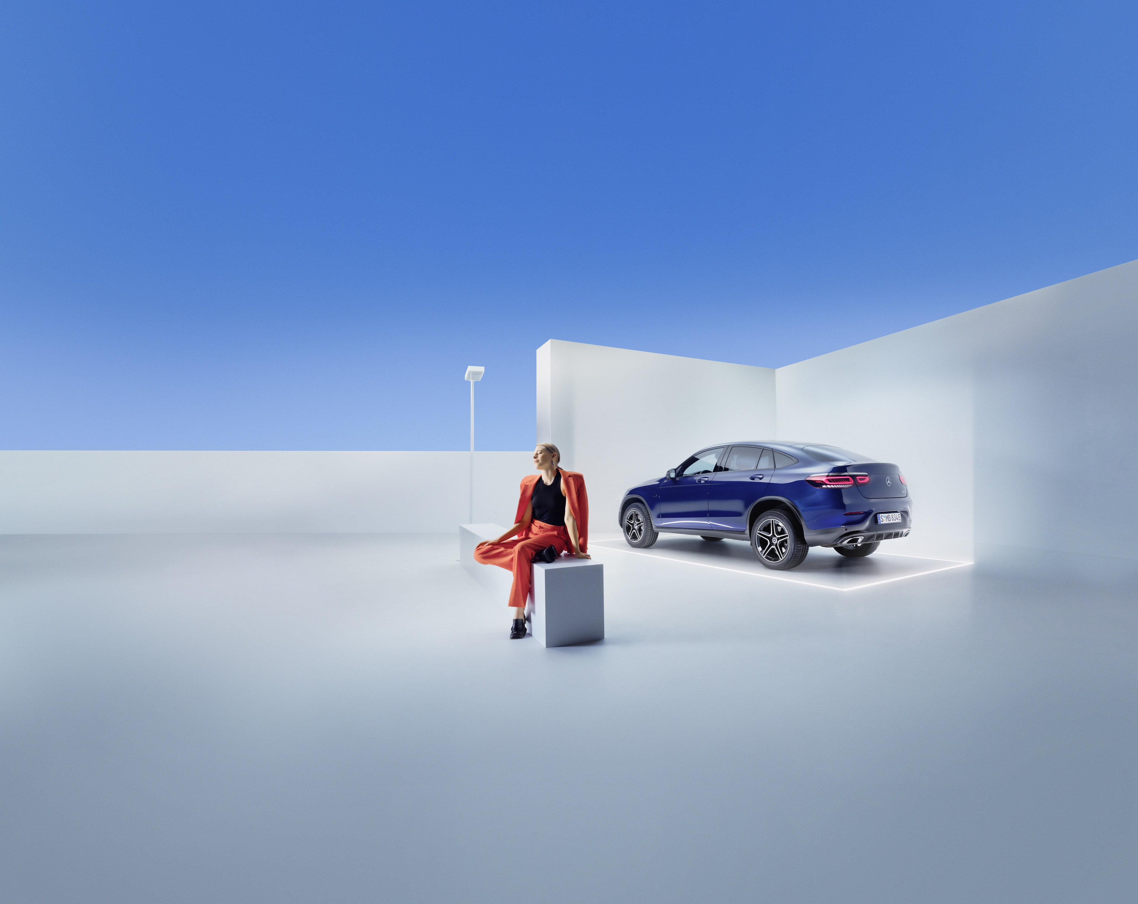 Mercedes-Benz Service Contracts A woman is sitting on a bench in front of a Mercedes-Benz.