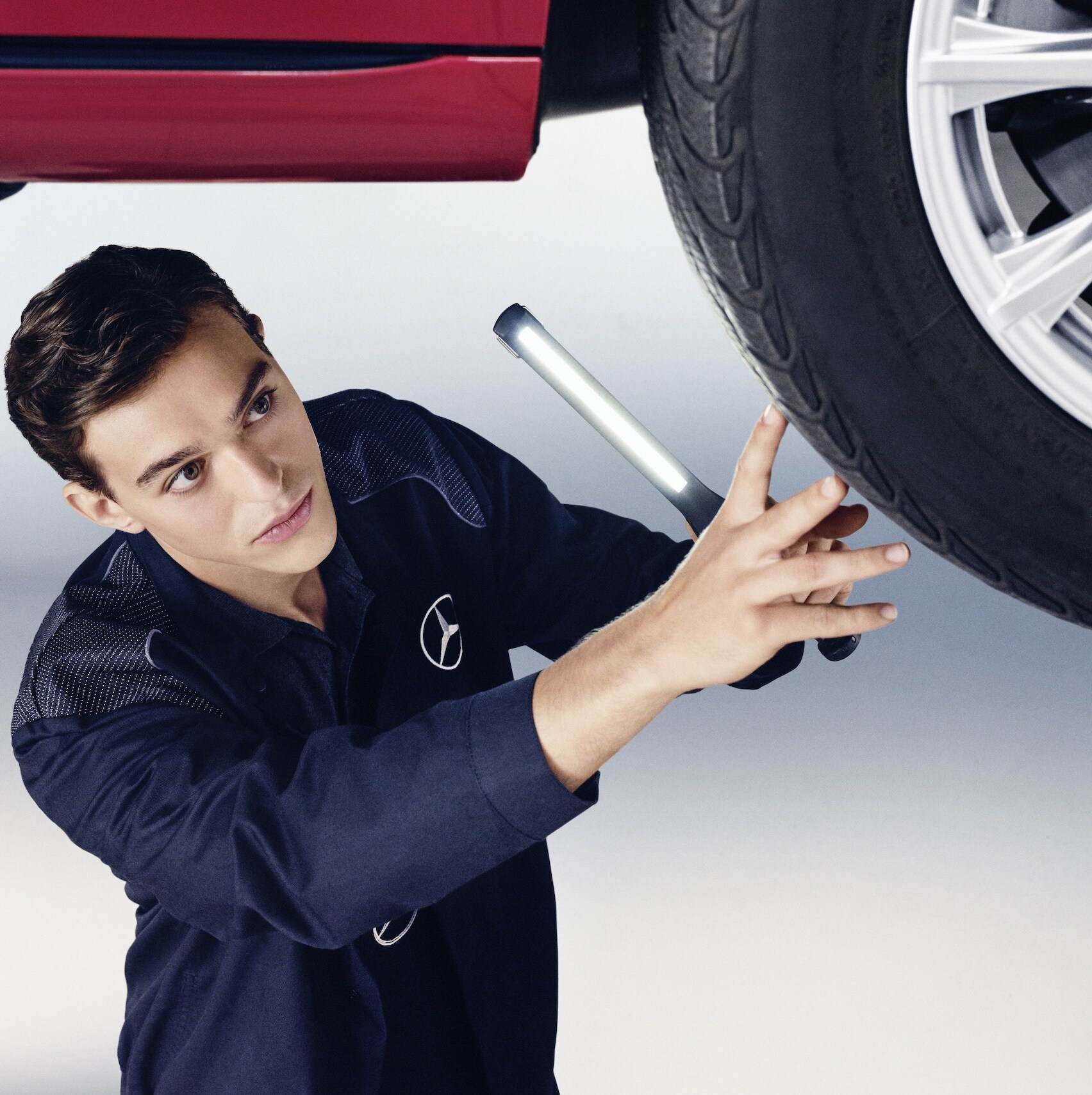 一位 Mercedes-Benz 機械師正在檢查一輛 Mercedes-Benz 的車輪。