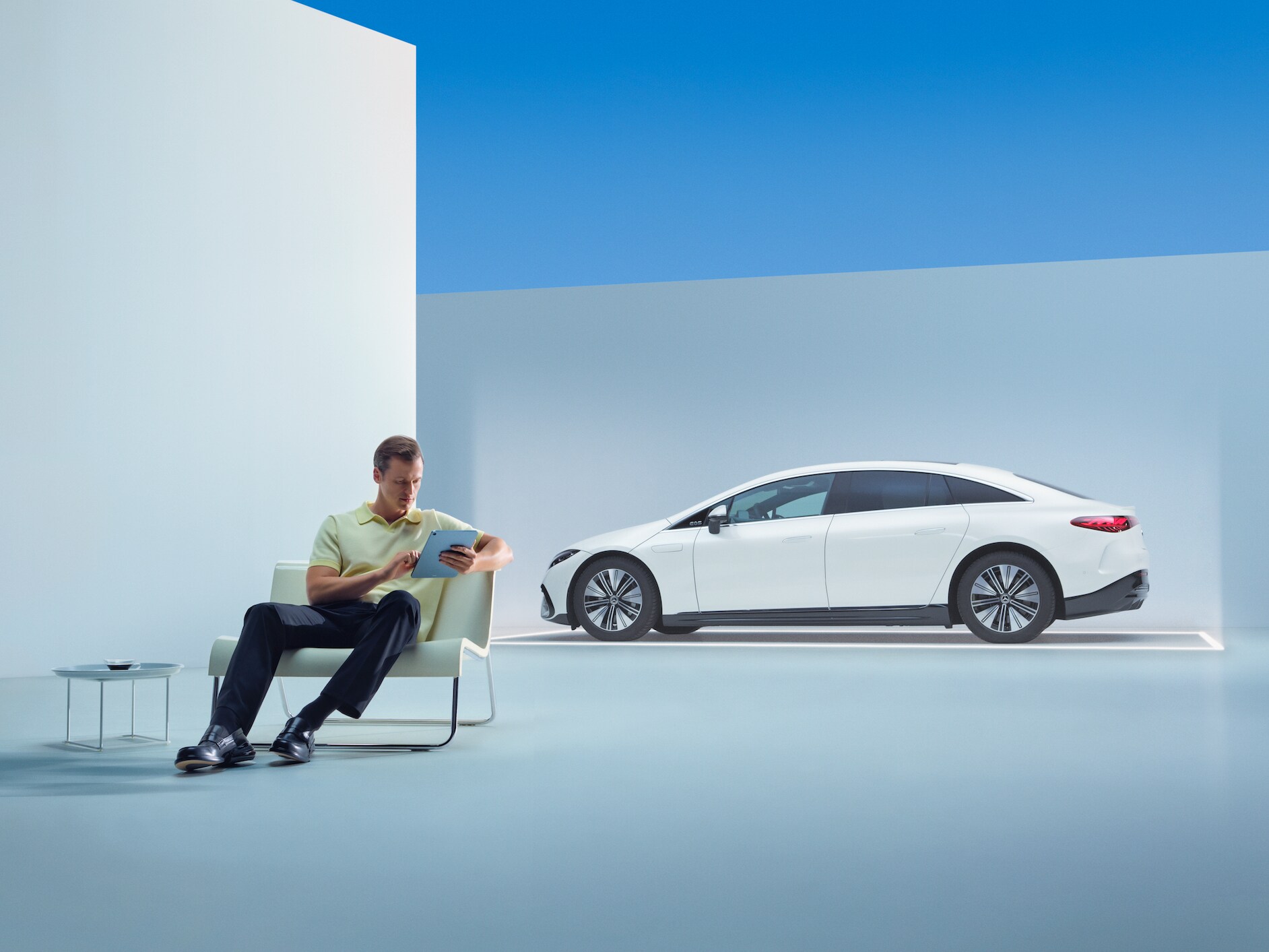 A person is sitting in front of his Mercedes with his tablet.