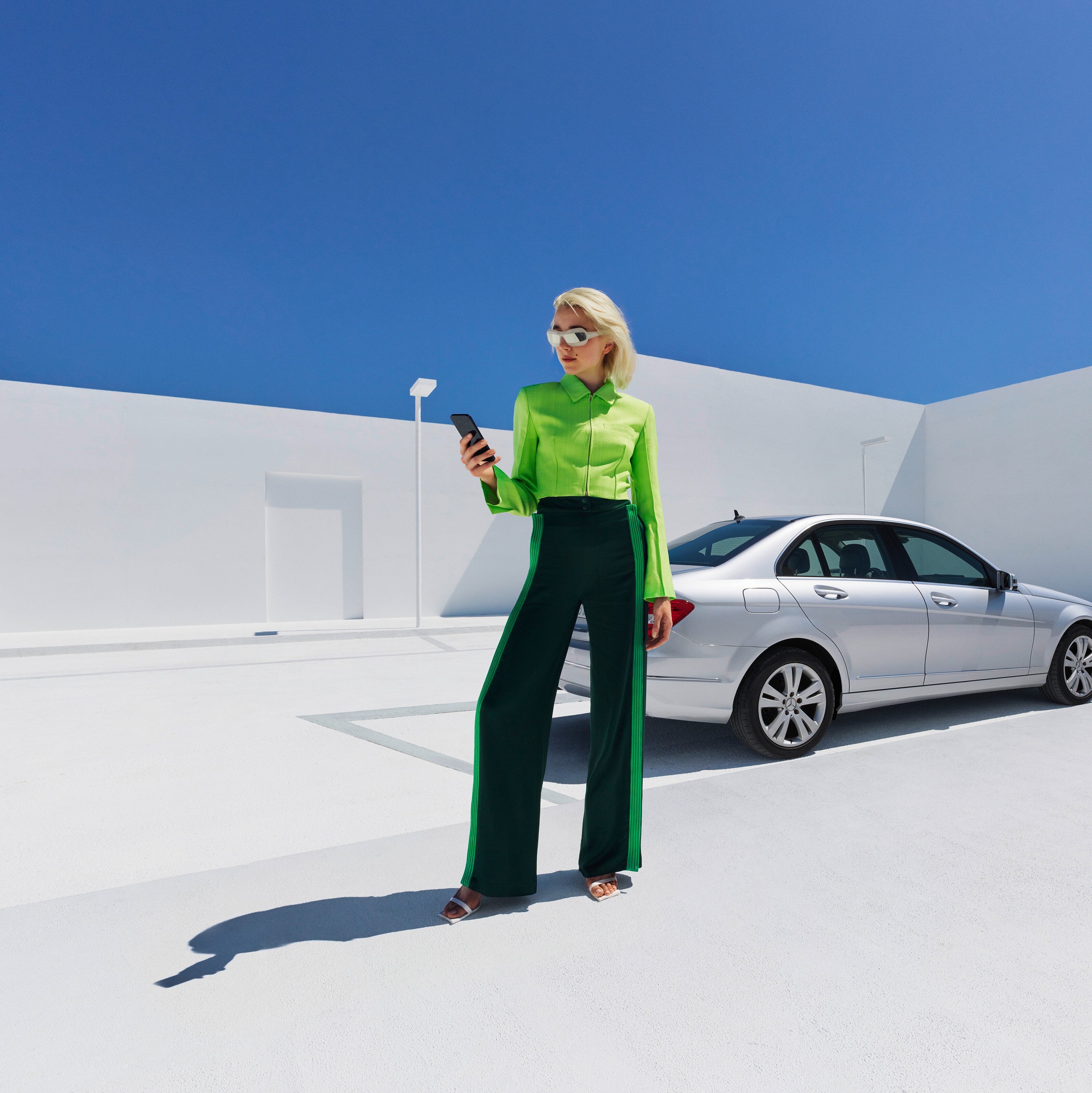 A lady holding mobile in front of a car