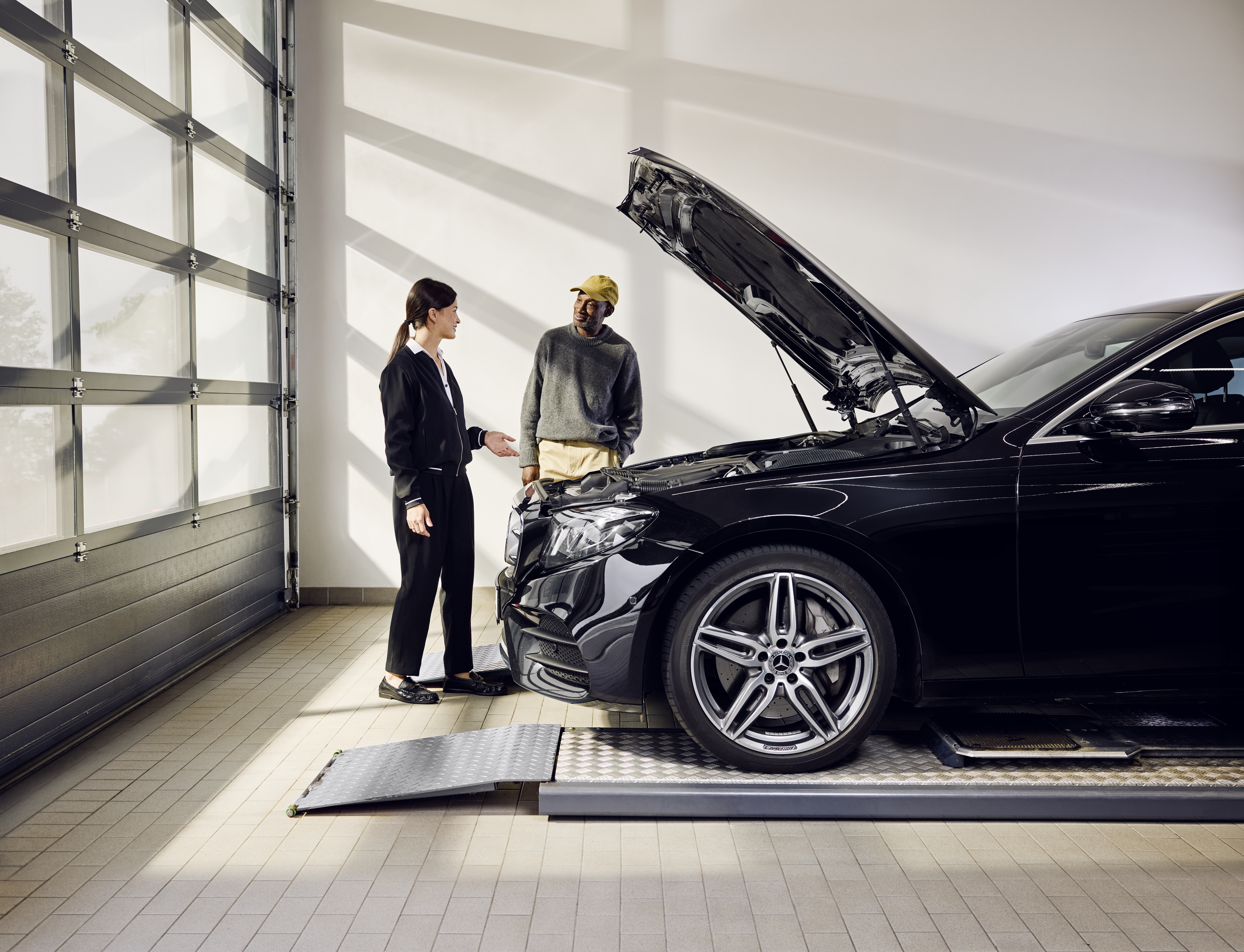 Mercedes-Benz Genuine Parts Replacement Mercedes‑Benz vehicle positioned on a service ramp with the bonnet open during a professional exchange of genuine parts at a service center.