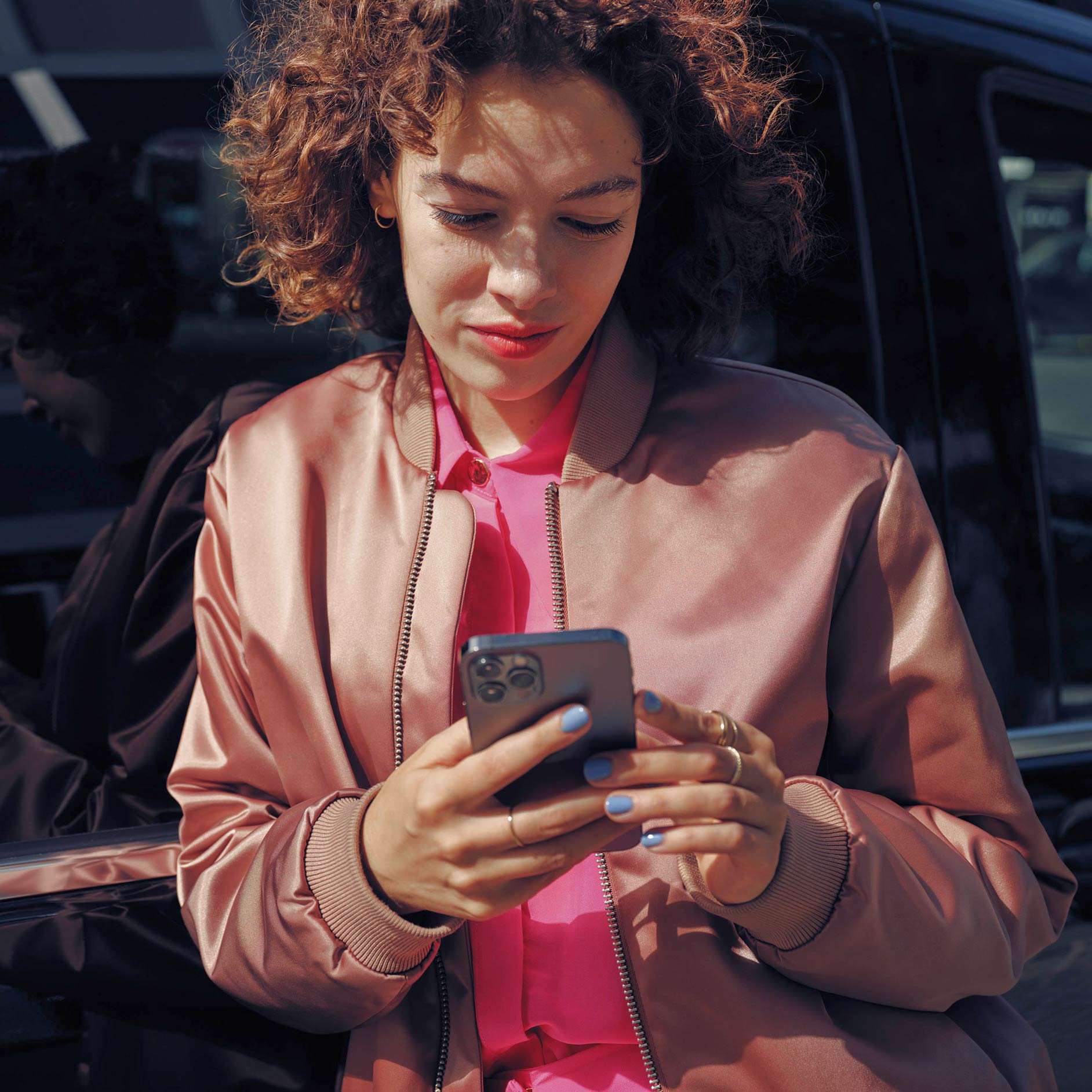 租用 | 金融服務 | Mercedes-Benz小型商用車 一位女士在黑色Mercedes-Benz EQV輕型客貨車旁邊使用流動電話