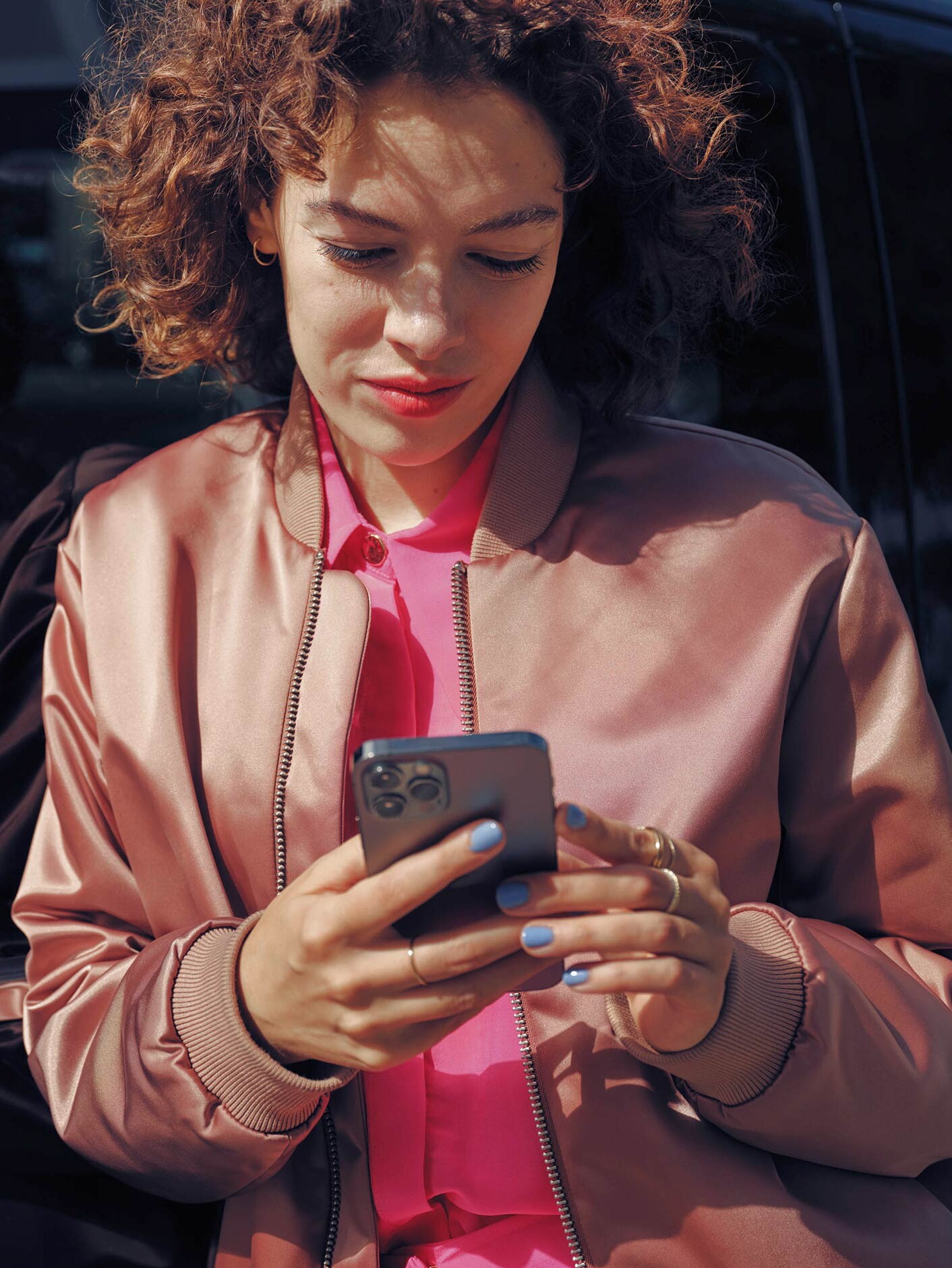 A woman on the phone next to a black Mercedes-Benz EQV van