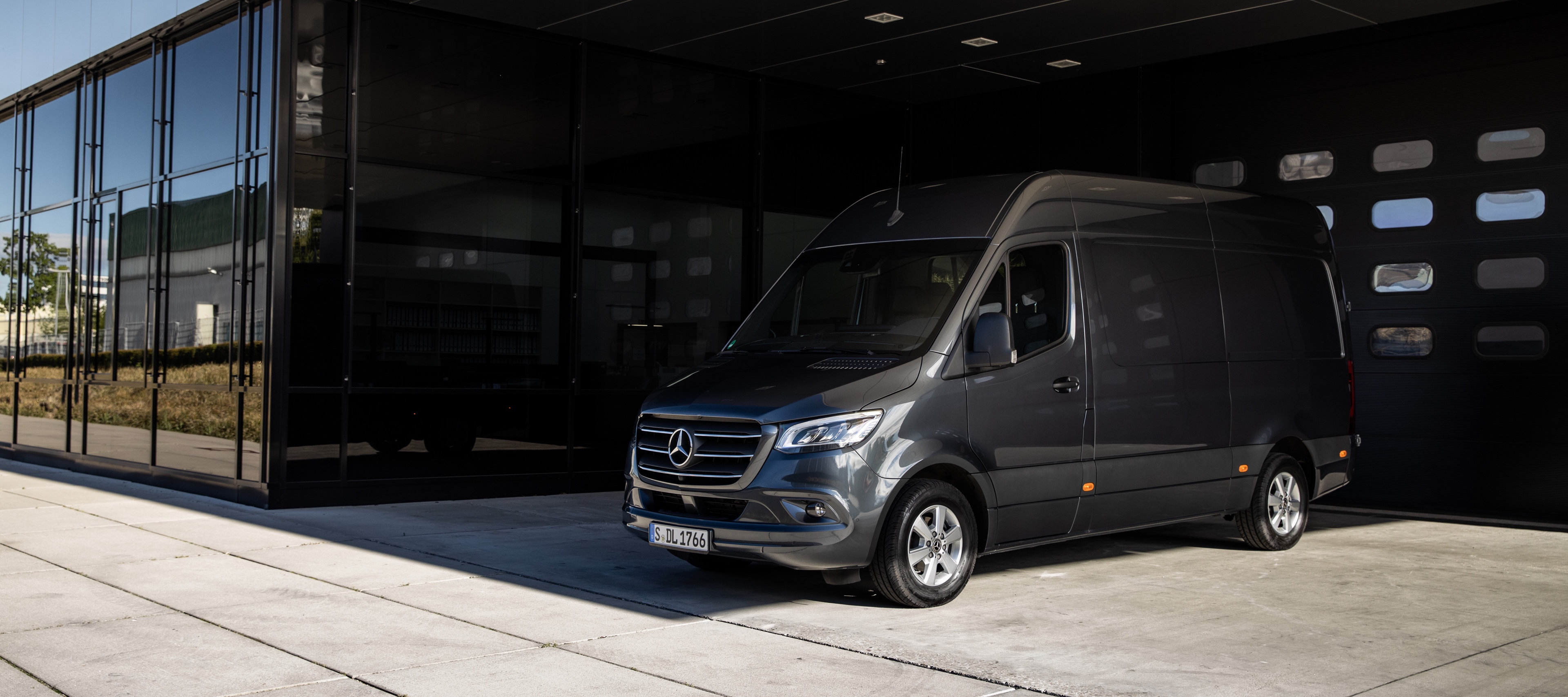 Sprinter Panel Van | Mercedes-Benz Vans A Sprinter panel van from Mercedes-Benz standing in front of a sliding gate in a modern courtyard.