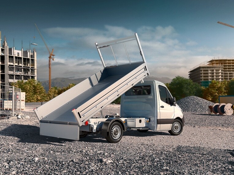 A Sprinter dropside van from Mercedes-Benz parked with the flatbed raised in the middle of a construction site.