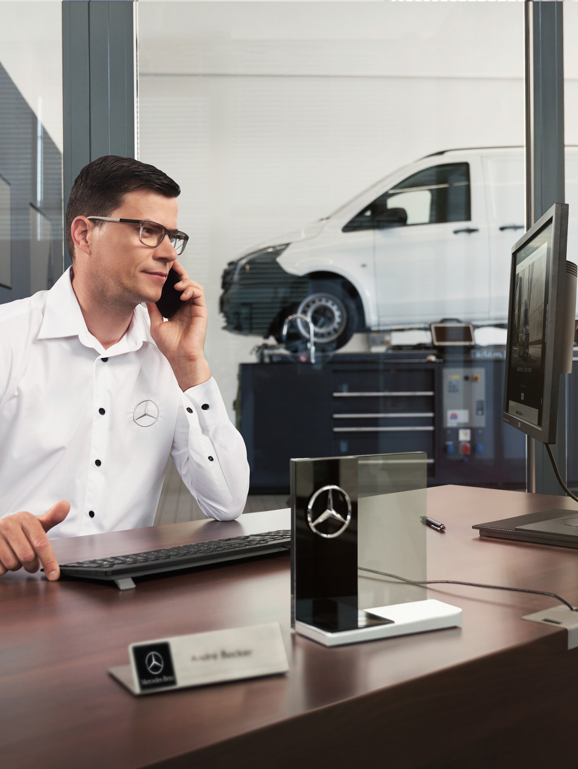 Mercedes-Benz Service Adviser talking on the phone in a workshop.