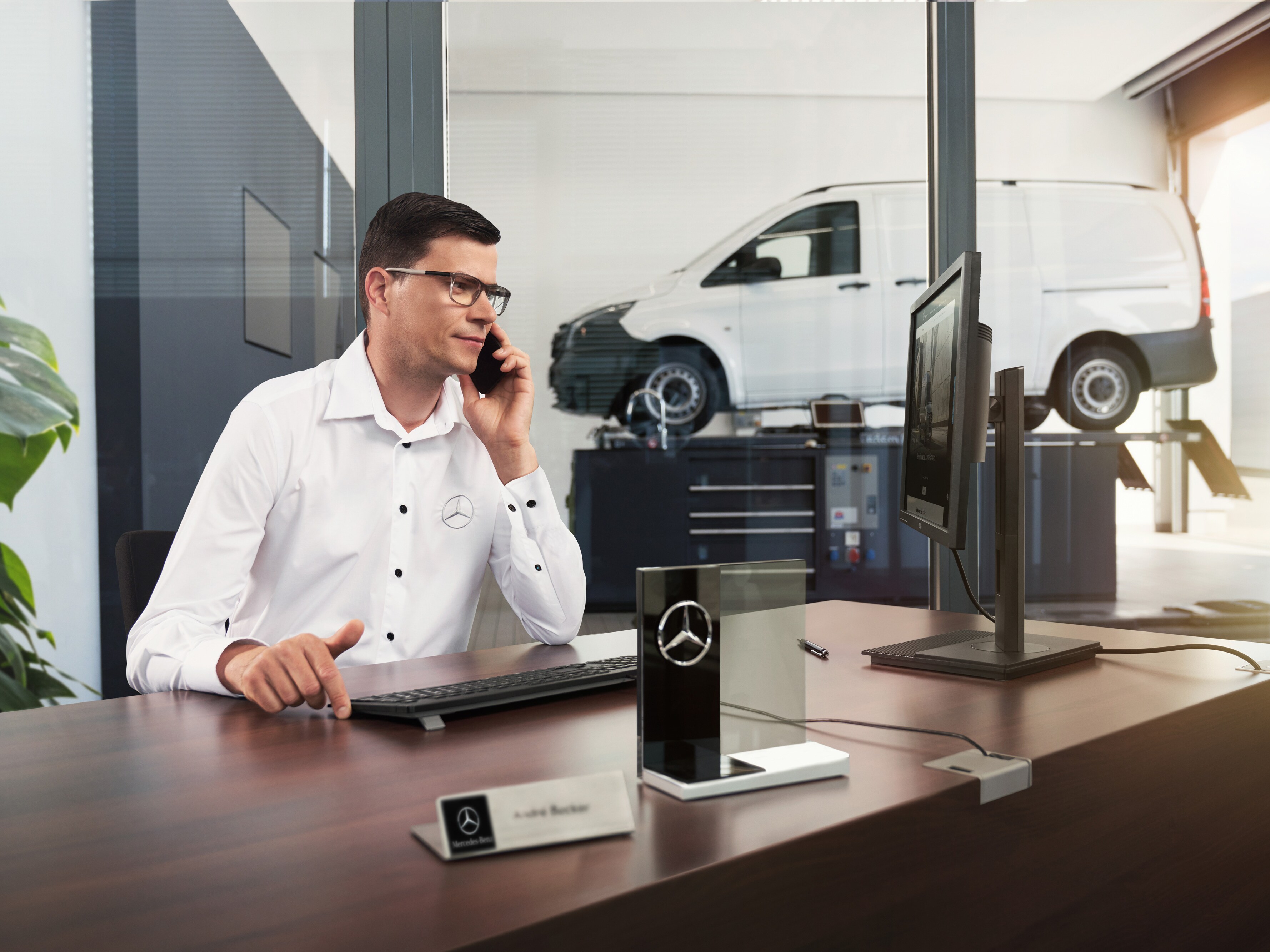 Mercedes-Benz Service Adviser talking on the phone in a workshop.
