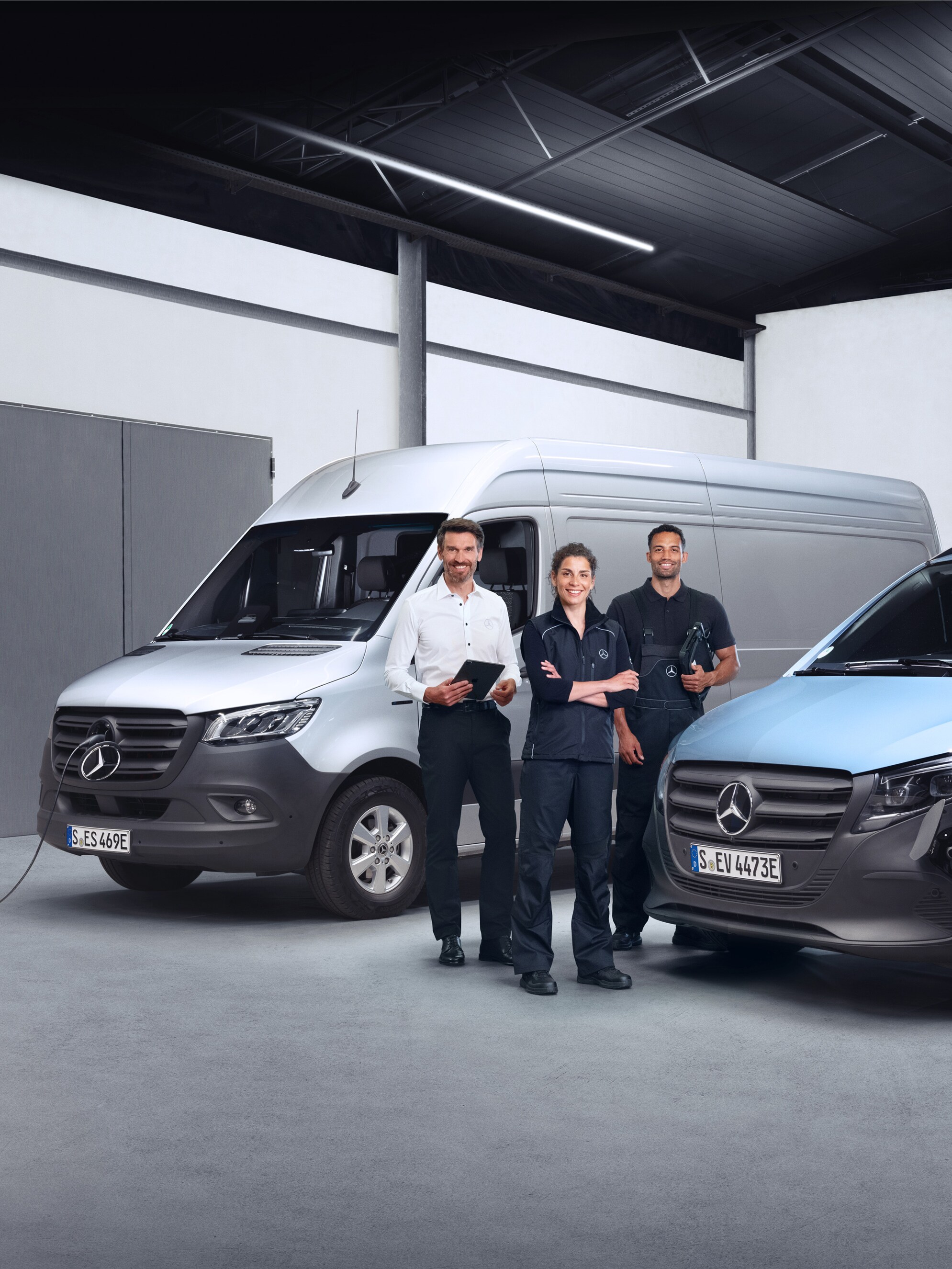 Three employees in front of Mercedes-Benz vans symbolising quality.