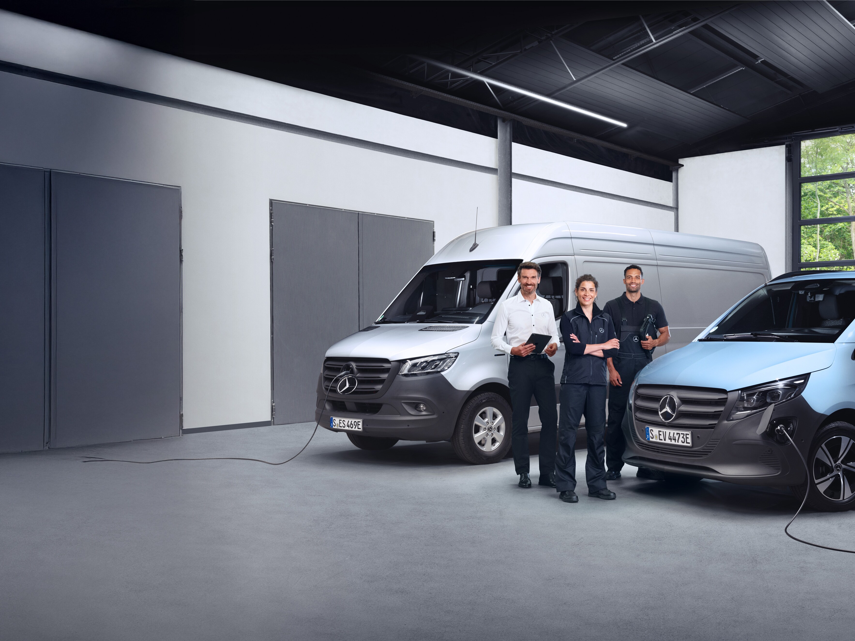 Three employees in front of Mercedes-Benz vans symbolising quality.
