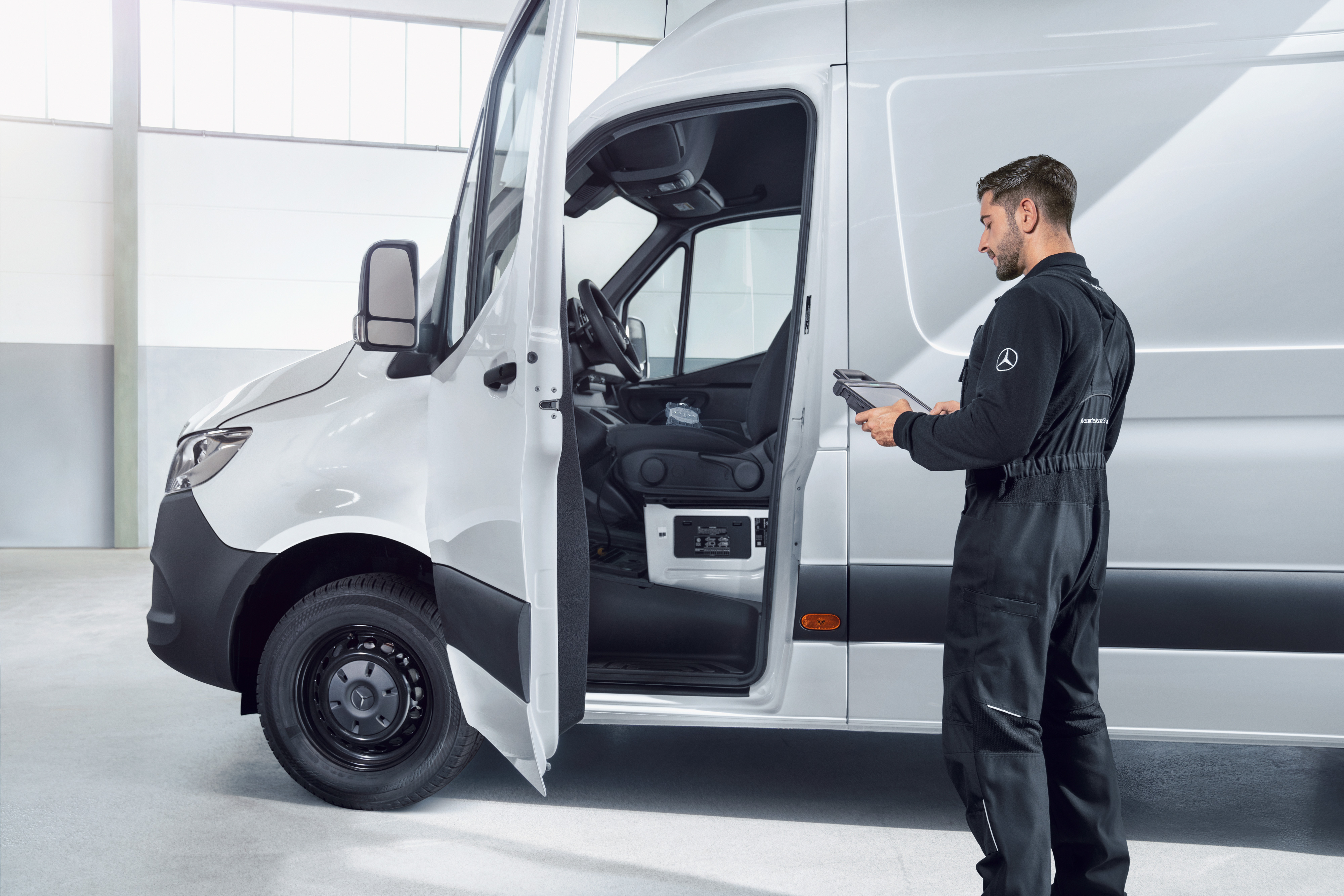 Mercedes-Benz | Vans quality overview Mechanic checking a white Mercedes-Benz van with a tablet, symbolising quality standards and the quality promise.