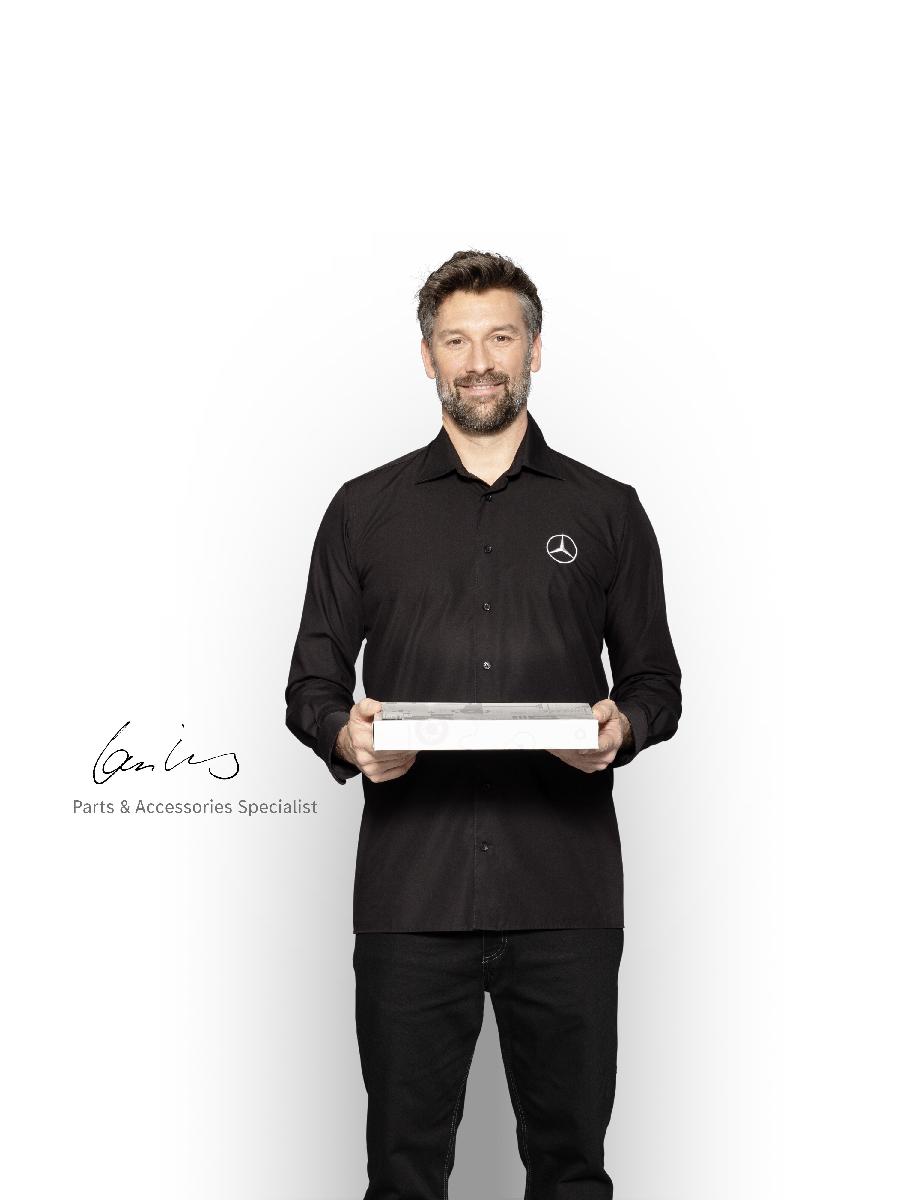 Mercedes-Benz Inhouse Technician with a box in his hands to show Mercedes-Benz genuine parts.