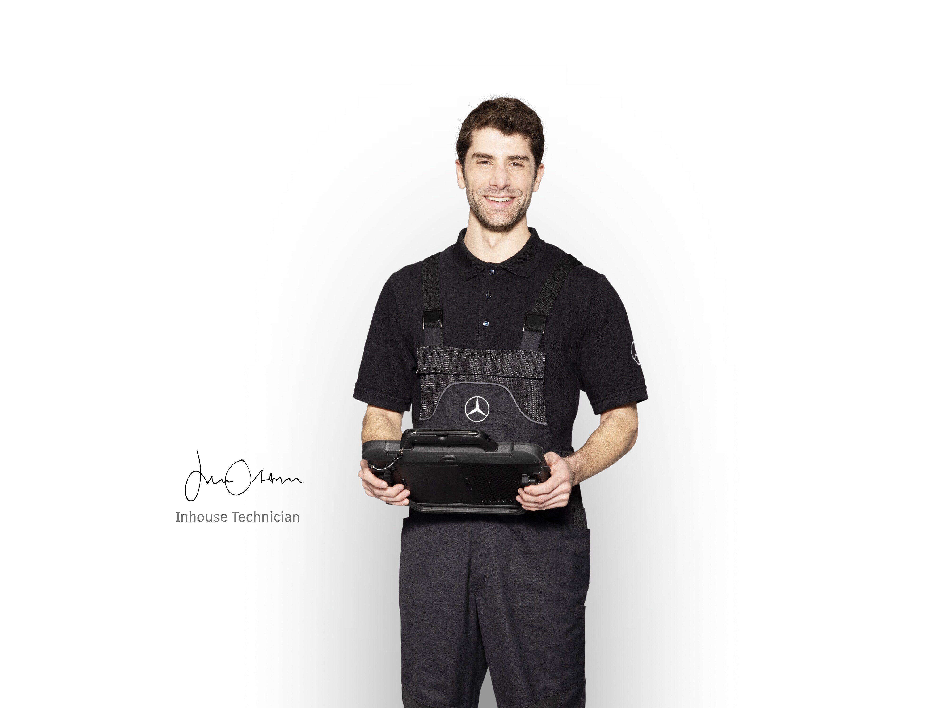 Mercedes-Benz mechanic in work clothes holding a tablet ready for damage reporting.