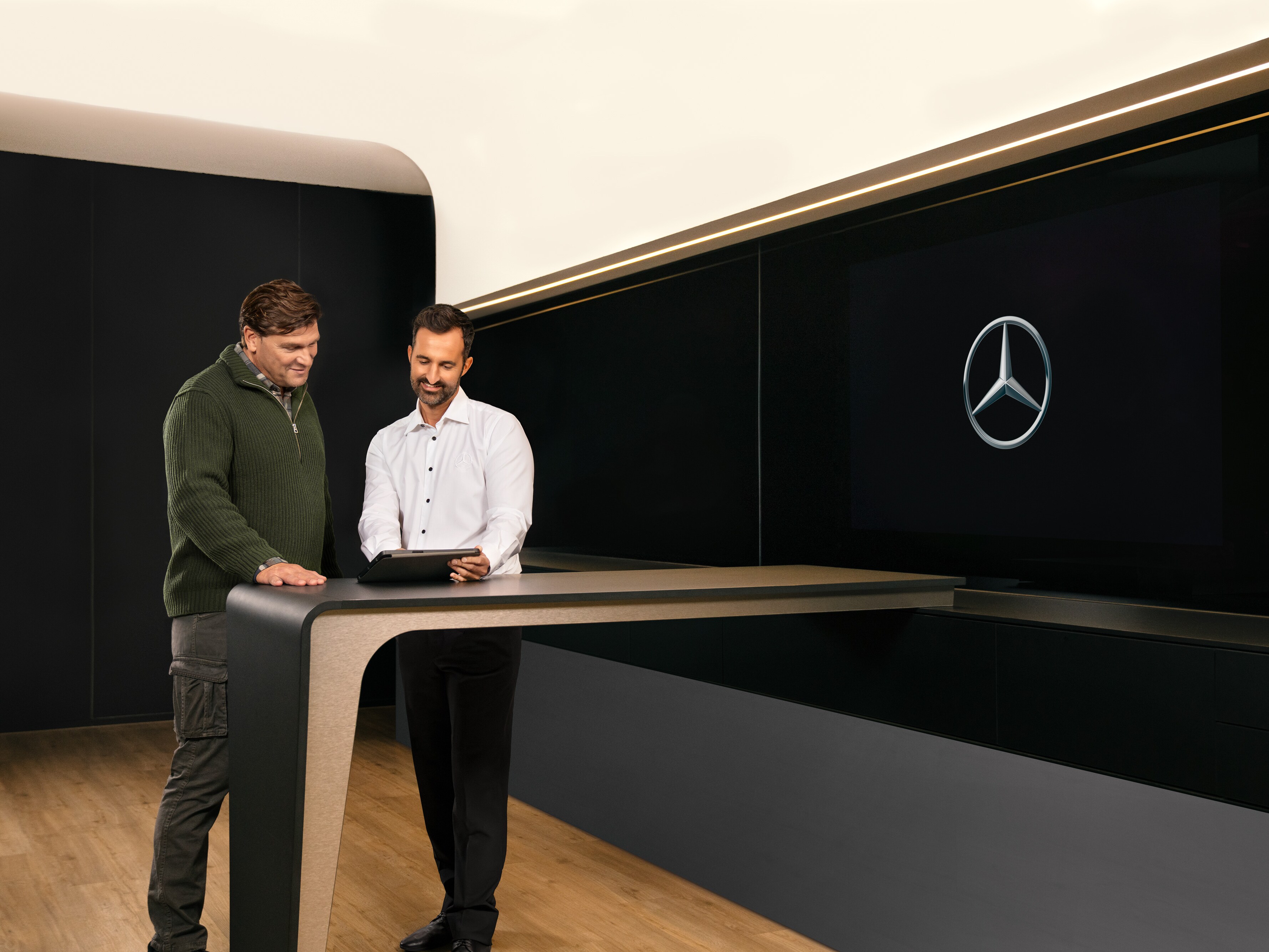 Two men having a consultation standing around a table looking at an iPad.