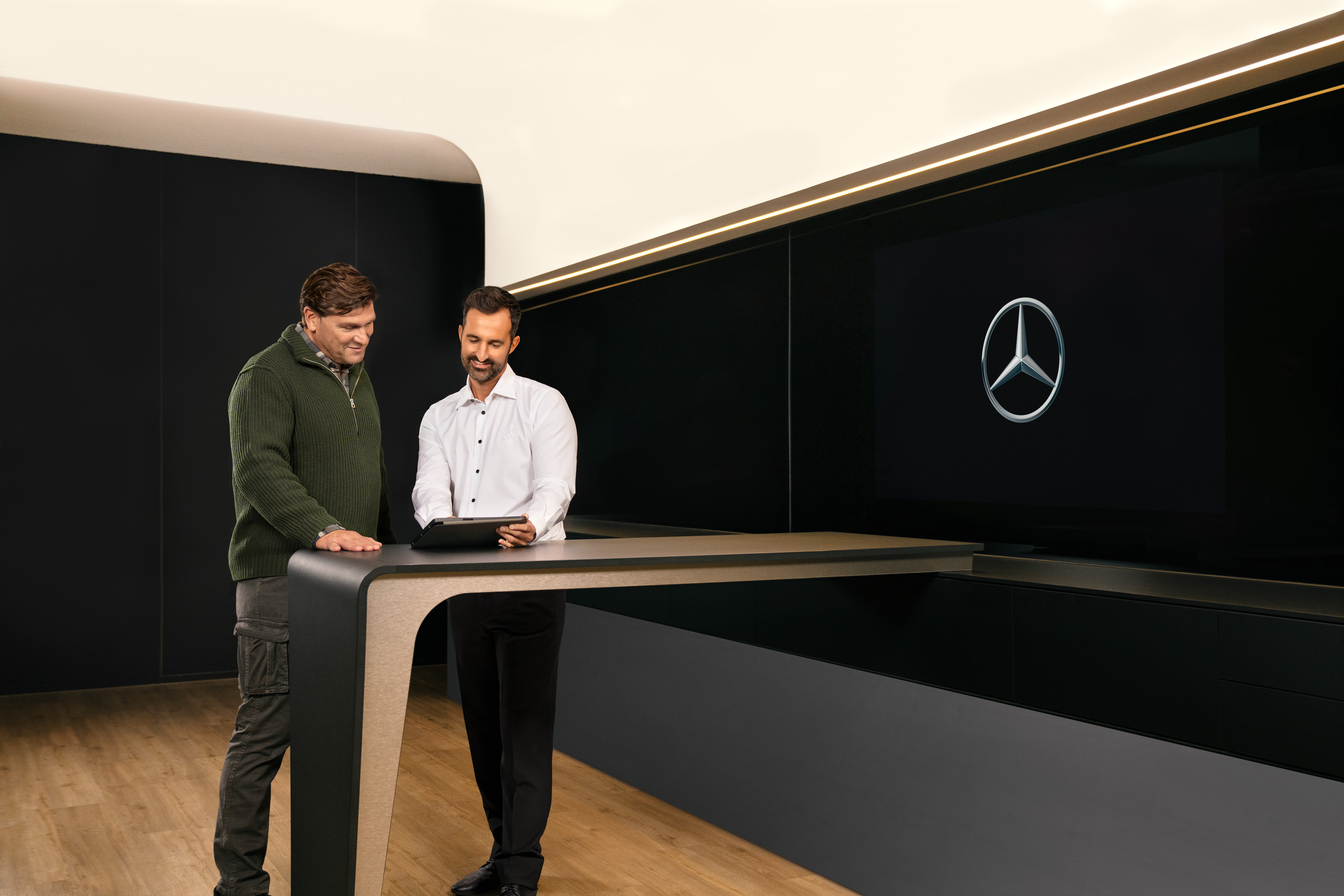 Mercedes-Benz | Van ServiceCare Two men having a consultation standing around a table looking at an iPad.