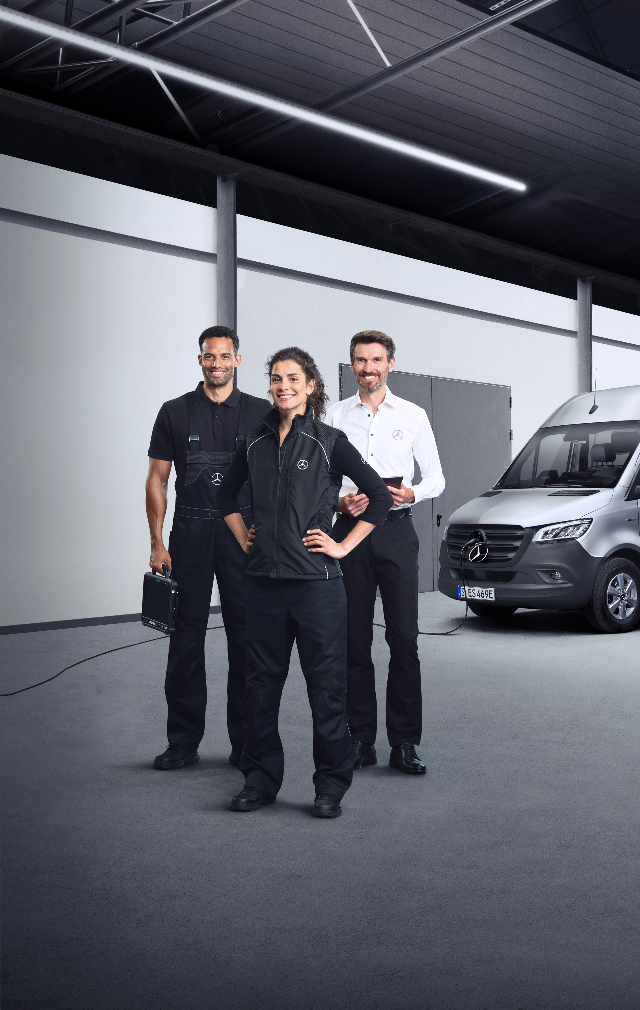 Mercedes-Benz | 服務概覽 | 電動小型商用車服務 三名員工站在連接有充電線的銀色 Mercedes-Benz eSprinter 前。