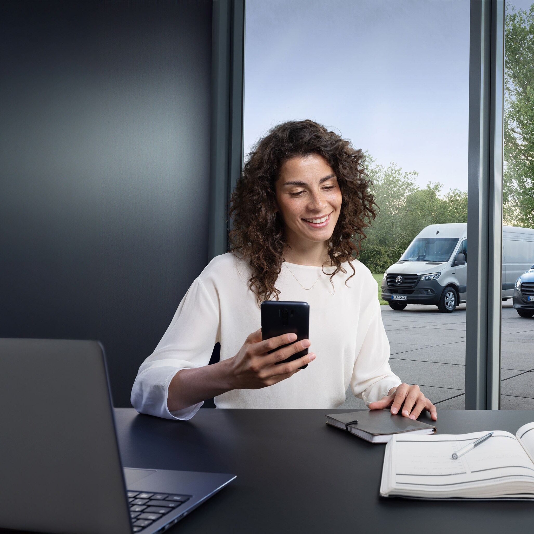 Customer on the phone in front of a range of Mercedes-Benz vans.