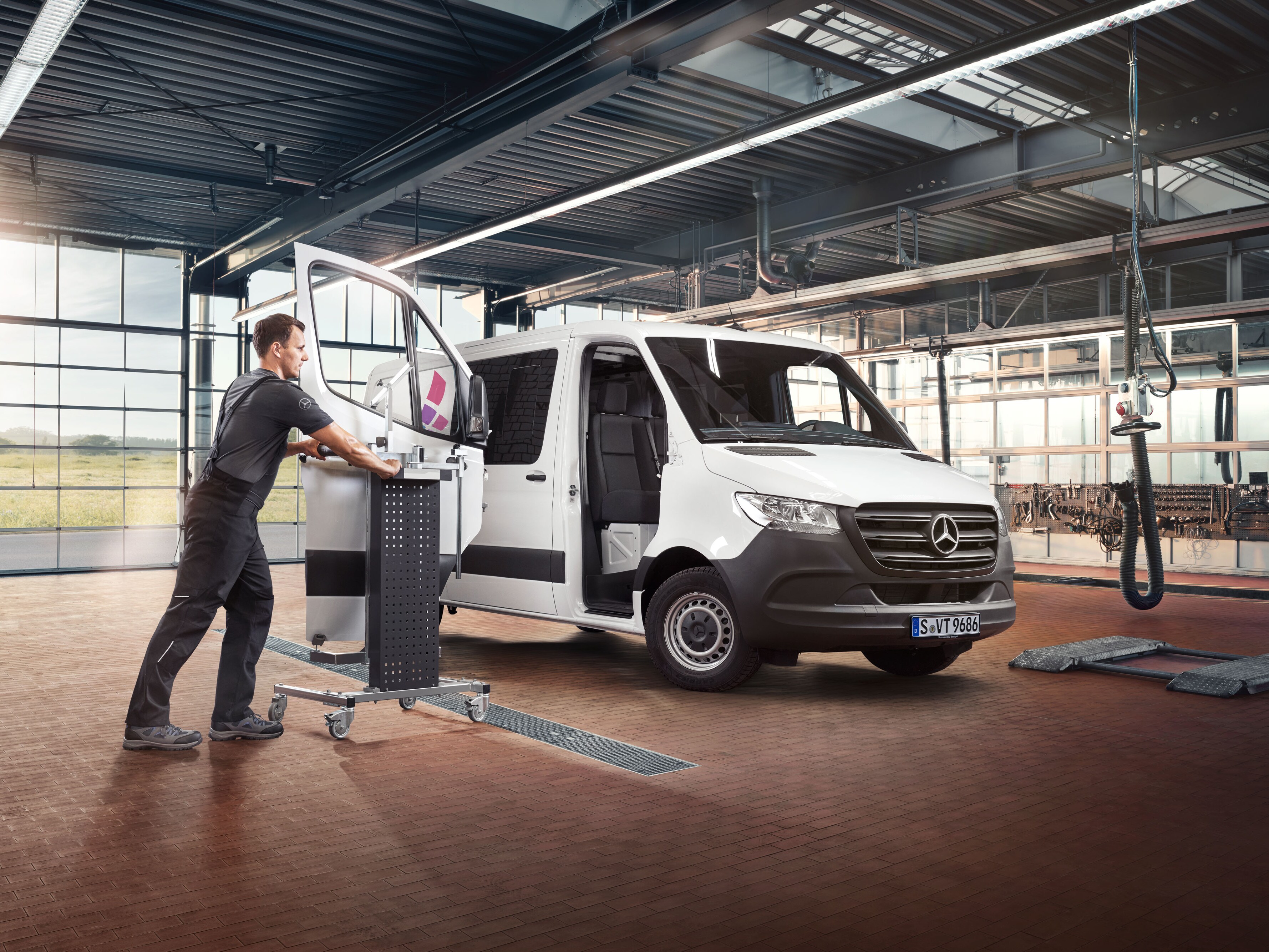 在白色 Mercedes-Benz Sprinter 上安裝車門的機械師。