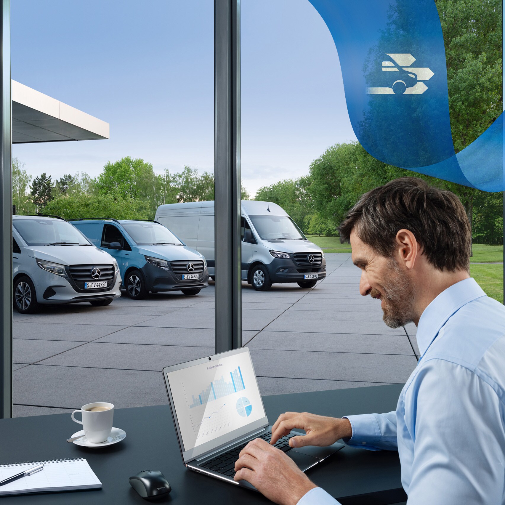一位男士在辦公室使用手提電腦，背景是一系列 Mercedes-Benz 小型商用車。