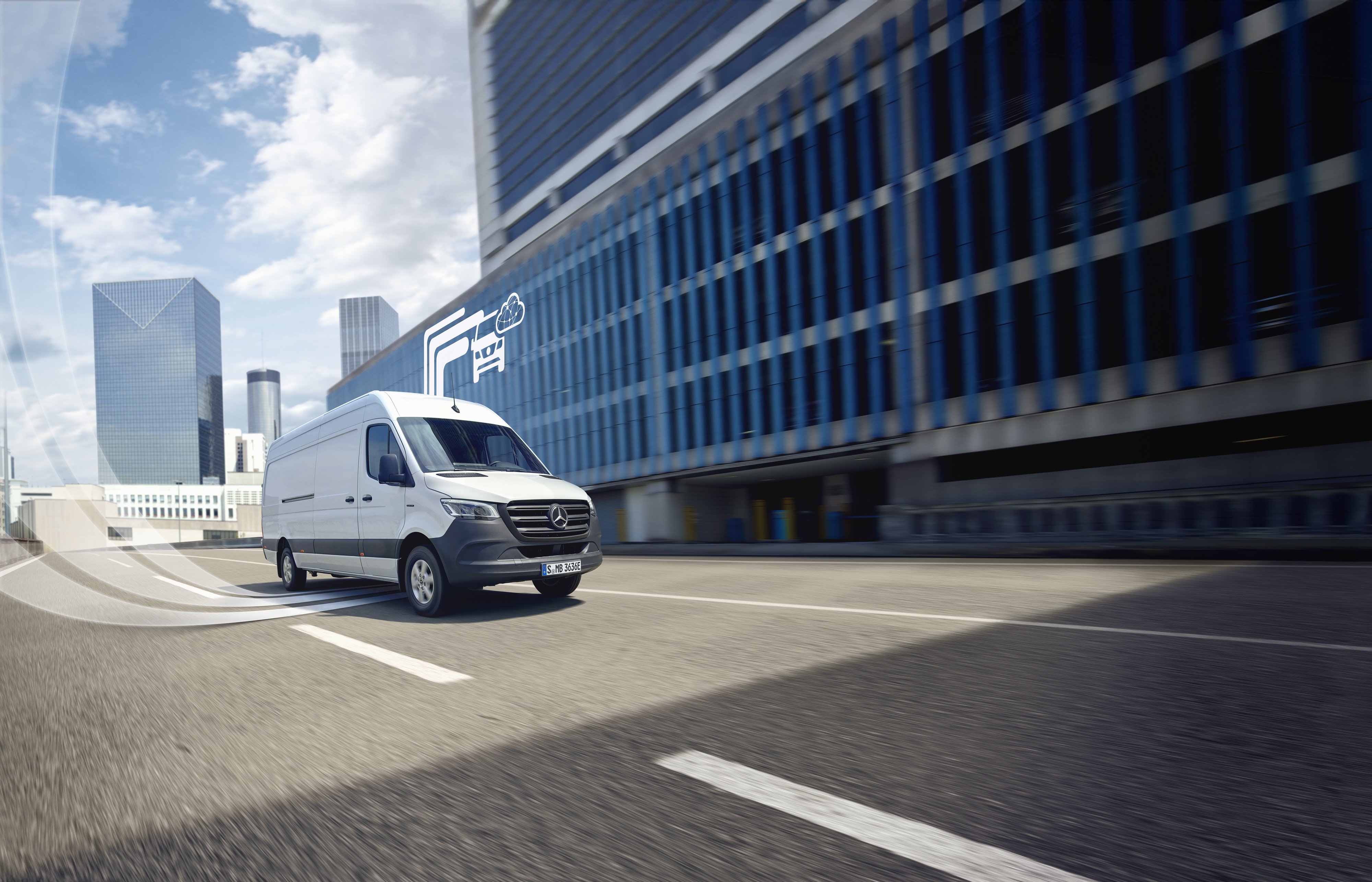 Mercedes-Benz | Van technology | Digital Extras White Mercedes-Benz van driving through the city, digital symbol of Mercedes-Benz technology in the background.